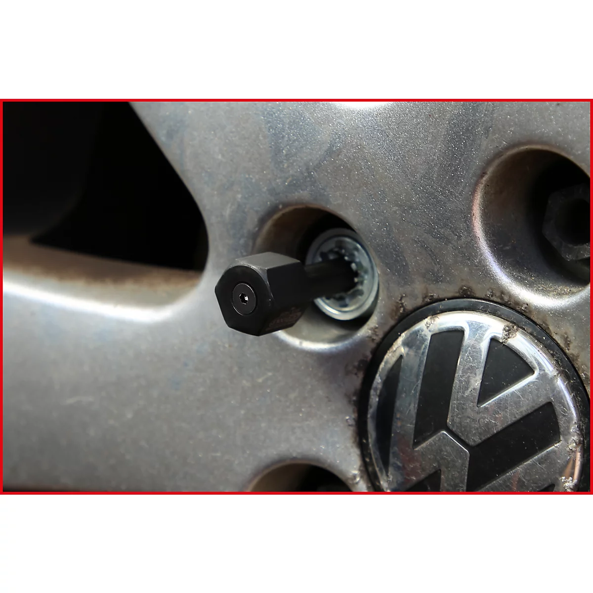 Nahaufnahme einer Felge mit einem speziellen Radmutternschlüssel. Das VW-Logo ist sichtbar.